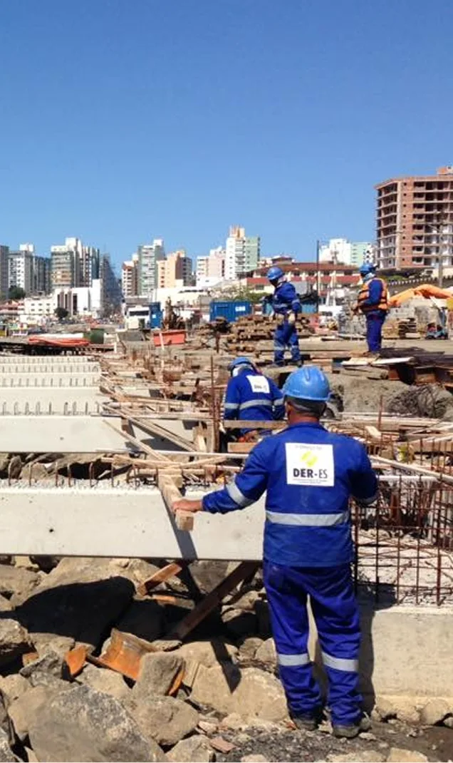 Equipe da Vetor Engenharia em obra à beira-mar, com prédios ao fundo